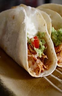 three tortillas with chicken, guacamole and tomatoes on them sitting on a table