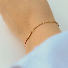 Close-up of hand wearing delicate bracelet of gold chain and red thread with gold beads detail at center. Elegant Friendship Bracelets With Adjustable Chain, Minimalist Adjustable Gold Bracelet With Chain, Minimalist Adjustable Gold Chain Bracelet, Minimalist Everyday Friendship Bracelets, Everyday Elegant Rose Gold Friendship Bracelets, Elegant Rose Gold Friendship Bracelets For Everyday, Minimalist Gold Friendship Bracelets For Everyday, Minimalist Gold Friendship Bracelet For Everyday, Elegant Yellow Gold Friendship Bracelets As Gift