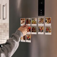 a person placing pictures on the side of a refrigerator with magnets attached to it