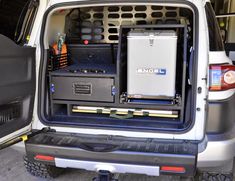 the back end of a white van with its doors open and electronics in the trunk