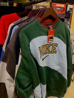 several sweatshirts are hanging on racks in a store, some with the word nike printed on them