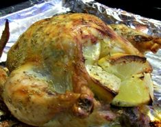 a roasted chicken on tin foil with lemon wedges