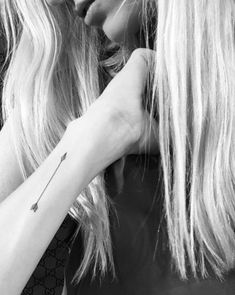 two women with long blonde hair and tattoos on their arms are looking at each other