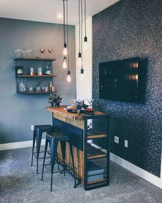 a bar with three stools in front of it and a television on the wall