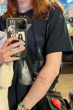 a woman holding a cell phone in her right hand with a star tattoo on it