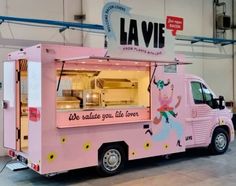 a pink food truck is parked in a building with the word lavie written on it