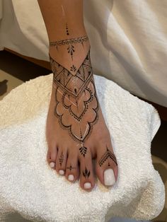 a woman's foot with tattoos on it sitting on top of a white towel