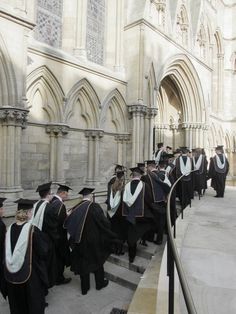 a group of men in gowns and hats standing on steps outside an old building