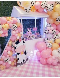 a pink and white birthday party with balloon decorations, balloons and an animal themed number