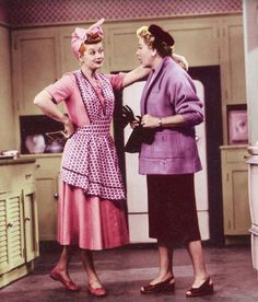 two women standing next to each other in a kitchen