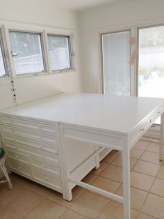 a white desk and chair in a room with tile flooring, windows, and tiled floors