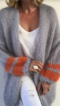 a woman sitting down wearing a gray and orange knitted cardigan with stripes on the sleeves