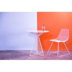 two chairs sitting next to each other in front of an orange and blue wall with a bottle on the table