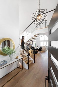 a woman is walking down the stairs in her home with wood floors and white walls