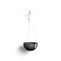 a black bowl hanging from a hook on a white wall