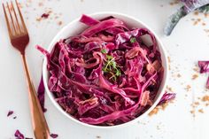 a white bowl filled with red cabbage next to a fork