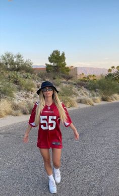 a woman in a football uniform is walking down the street