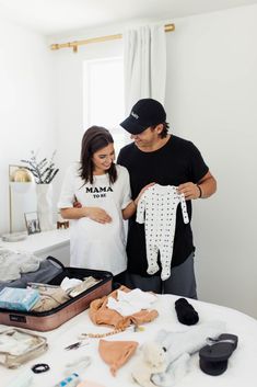 a man and woman looking at clothes on a table