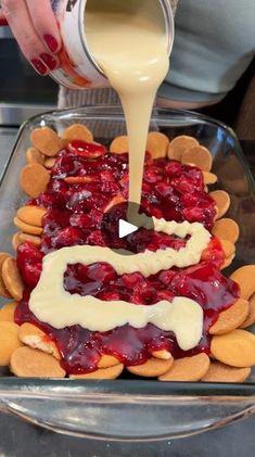 someone is pouring sauce on top of crackers in a glass dish with almonds