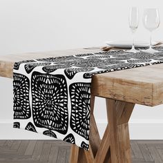 a wooden table topped with two wine glasses and a black and white table cloth on top of it