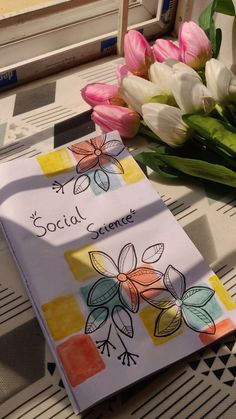 some flowers are sitting on a table next to a card with the words social science written on it