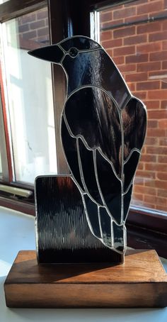 a stained glass bird sitting on top of a wooden block