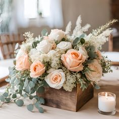 a wooden box filled with flowers and greenery on top of a table next to a candle