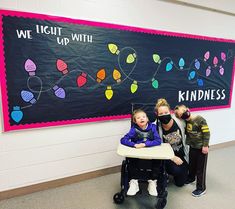 three children in front of a blackboard with lights on it and one child sitting in a stroller