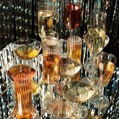 many glasses are stacked on top of each other with different colored liquids in them,