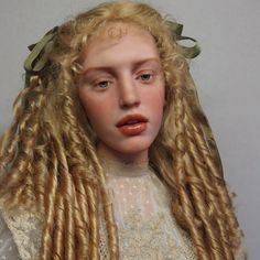 a close up of a doll with long blonde hair and braids on her head