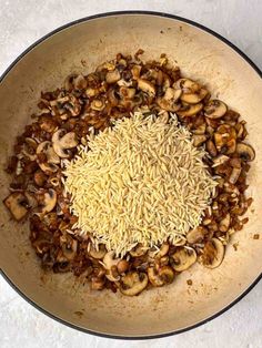 mushrooms and rice in a pan on a white counter top with a black border around it