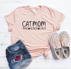 "Custom Cat Mom Shirt - Cat Mom Shirt - Cat Owner Tee - Cat Names Shirt - Gift For Cat Lover - Cat Mom T Shirt - Custom Cat Shirt with Names Welcome to Momaste Clothing Etsy Shop! This listing is for ONE (1) Unisex Cotton/Poly Shirt that says \"Cat Mom\" with custom cat names printed underneath. *Unisex runs longer, as it is a mens tee..we prefer this fit personally! *Super soft cotton/poly material COLORS: 20 color options! Color chart shown in listing photos. SIZES: XS-4XL UNISEX fit. These ar Cat Mom Shirt Ideas, Slogan Tee, Cat Tee, Cat Names, Custom Cat, Cat Shirts