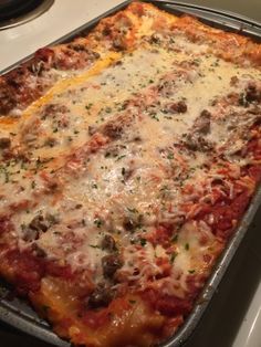 a casserole dish with meat, cheese and sauce on it sitting on a stove