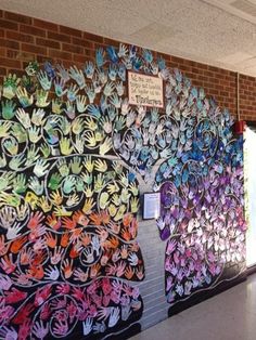 there are many handprints on the wall in this school hallway that is decorated with flowers and leaves