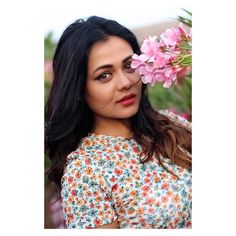 a woman with flowers in her hair posing for the camera and looking at the camera