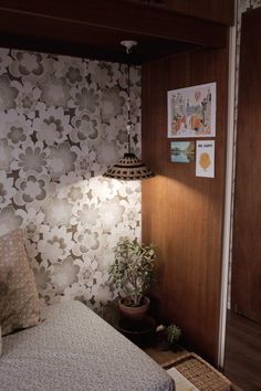 a bed sitting under a lamp on top of a wooden shelf next to a wall