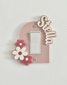 a pink light switch cover with flowers and the word stella on it's side