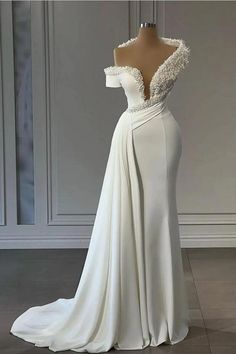 a white wedding dress on display in front of a wall