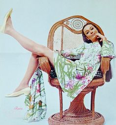 a woman sitting in a wicker chair with her legs crossed and wearing high heels