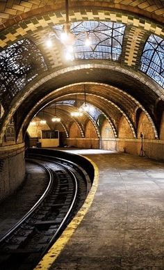 an empty train station with the lights on and tracks running parallel to it's platform