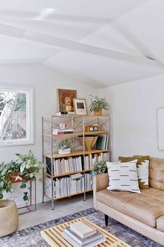 a living room filled with furniture and bookshelves next to a window on top of a rug