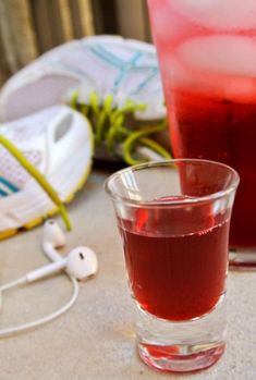 two glasses filled with liquid sitting on top of a table next to shoes and headphones