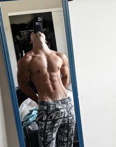 a shirtless man taking a selfie in front of a mirror