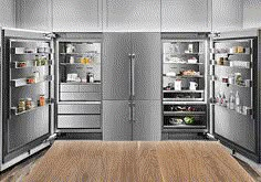 two stainless steel refrigerators are open in a kitchen with wood flooring and white cabinets