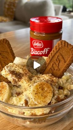 a glass bowl filled with food next to a jar of biscuits on top of a wooden table