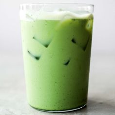 a glass filled with green liquid on top of a table