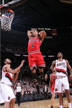 a basketball player jumping up to dunk the ball in front of two other players