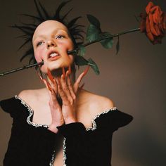 a woman with her hands on her face and roses in front of her head, posing for the camera