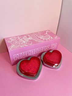 two red heart shaped lights sitting in front of a pink box