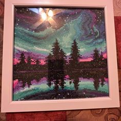 a painting made out of beads with trees in the foreground and a sky background